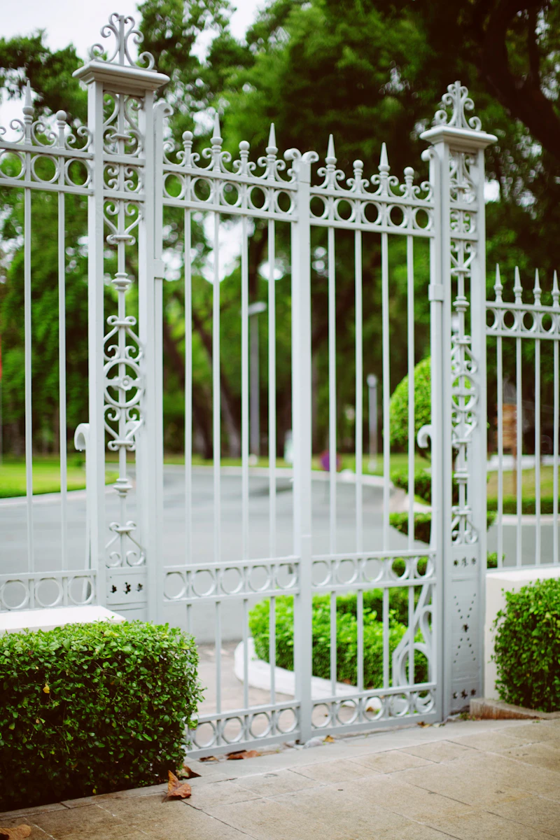 Portão de metal branco com plantas ao redor