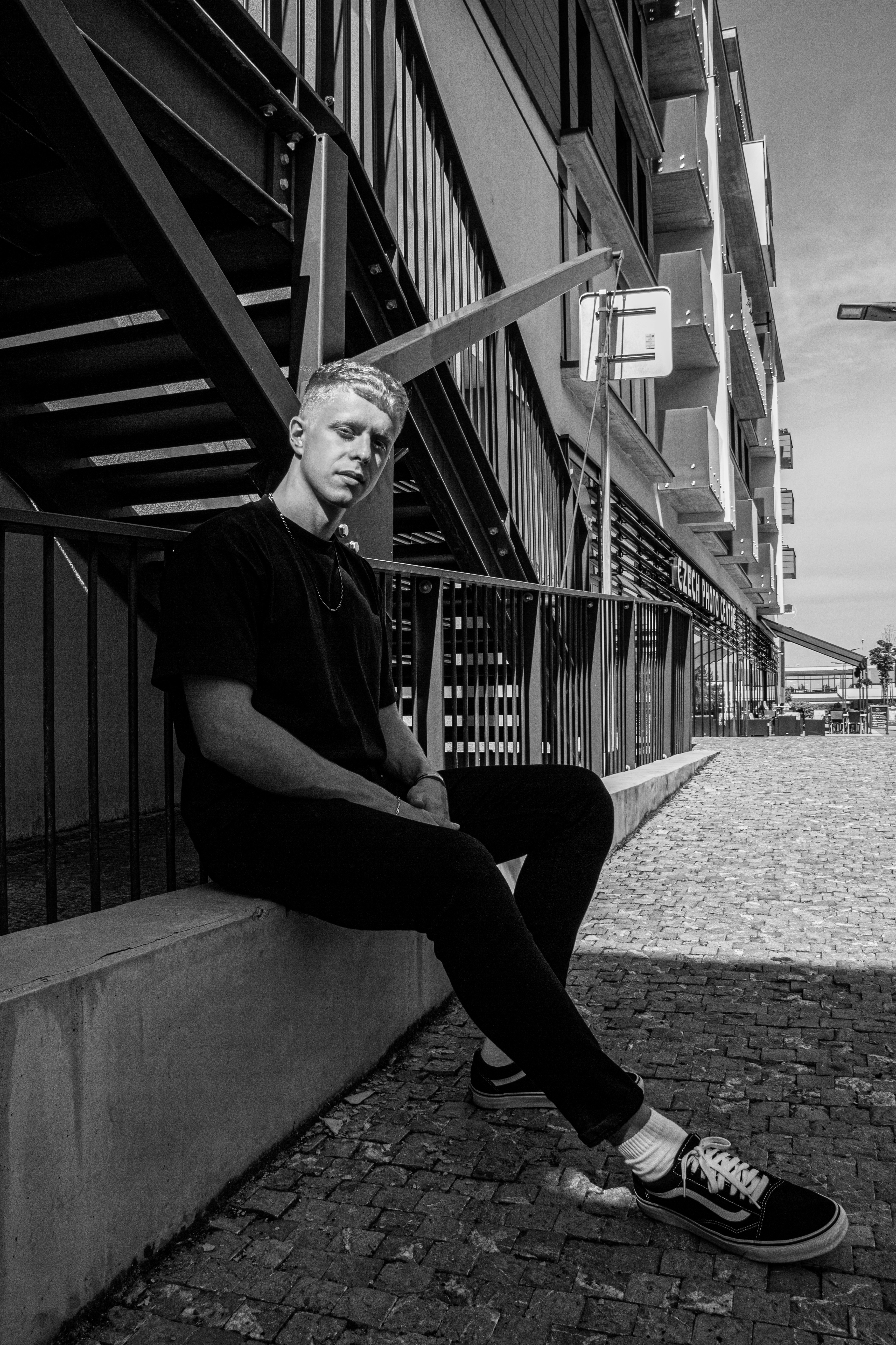 man in black shirt and pants sitting on concrete bench
