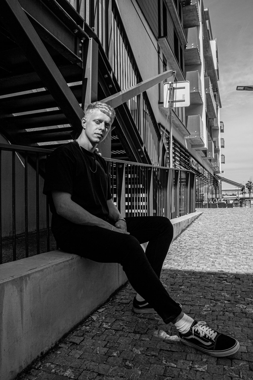 man in black shirt and pants sitting on concrete bench