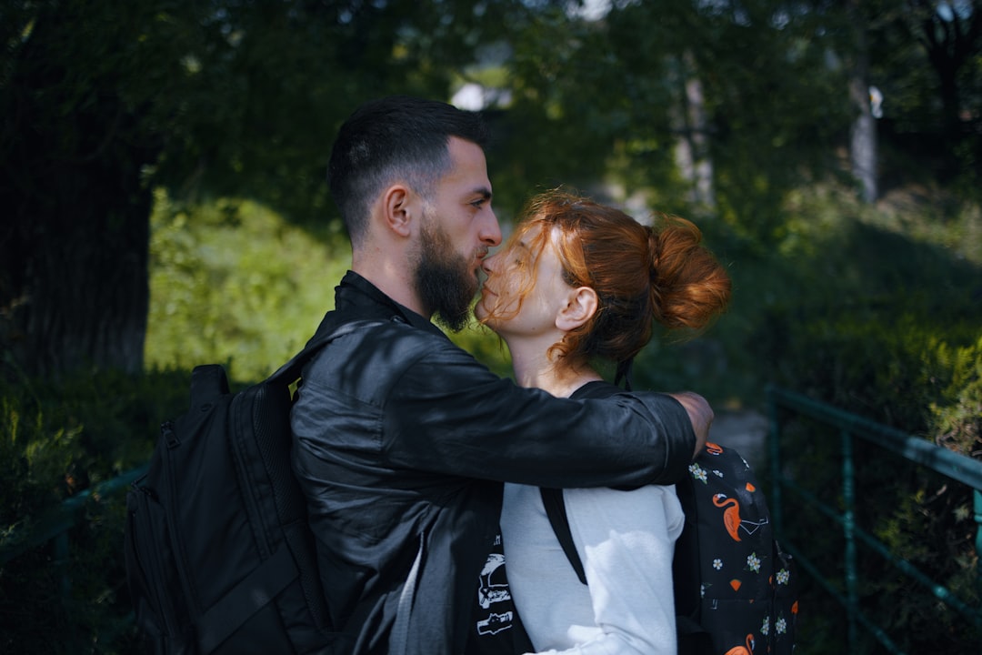 man in black jacket kissing woman in white shirt