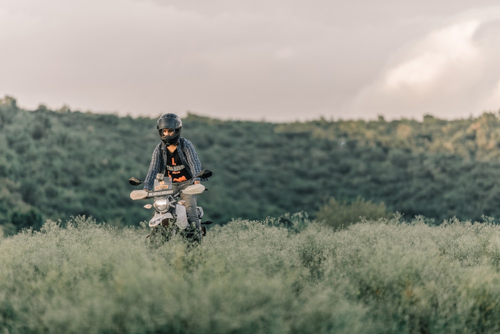 man in black jacket and black pants sitting on black motorcycle on green grass field during