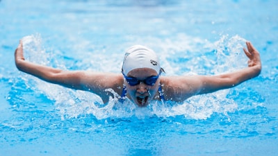 A coach giving personalized feedback to a teen swimmer practicing butterfly stroke.