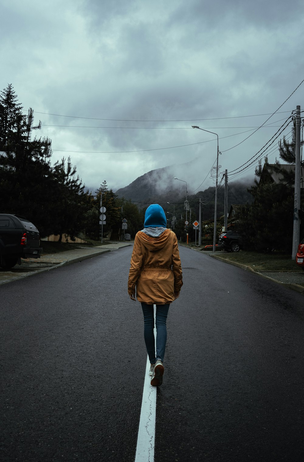 woman in brown coat standing on road during daytime