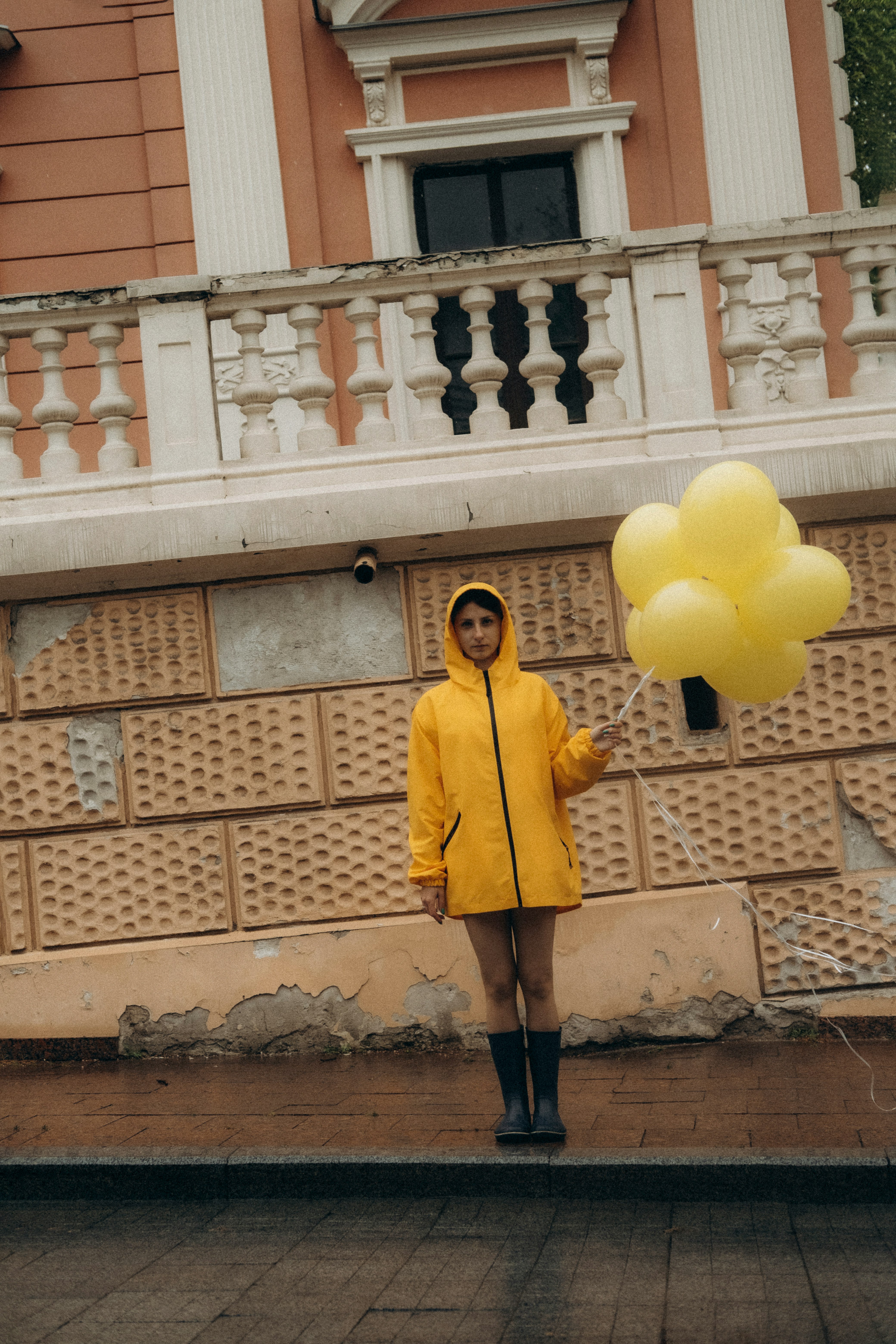 woman in yellow coat holding yellow balloons