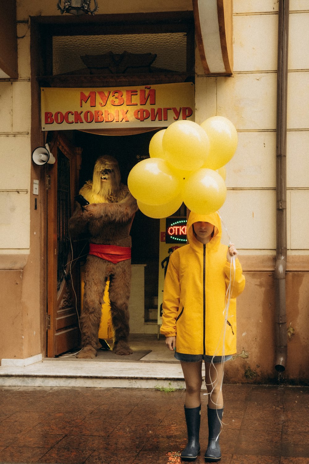 woman in yellow coat holding yellow balloons