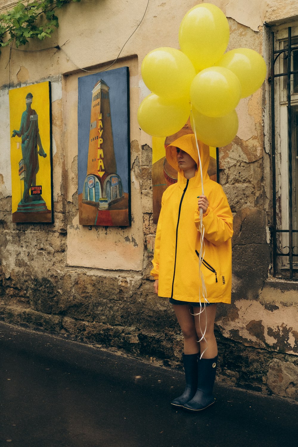 woman in yellow coat standing on gray concrete wall