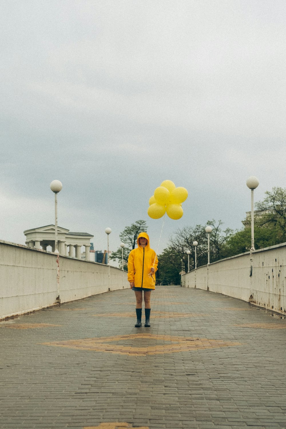woman in yellow jacket and black pants holding yellow balloons