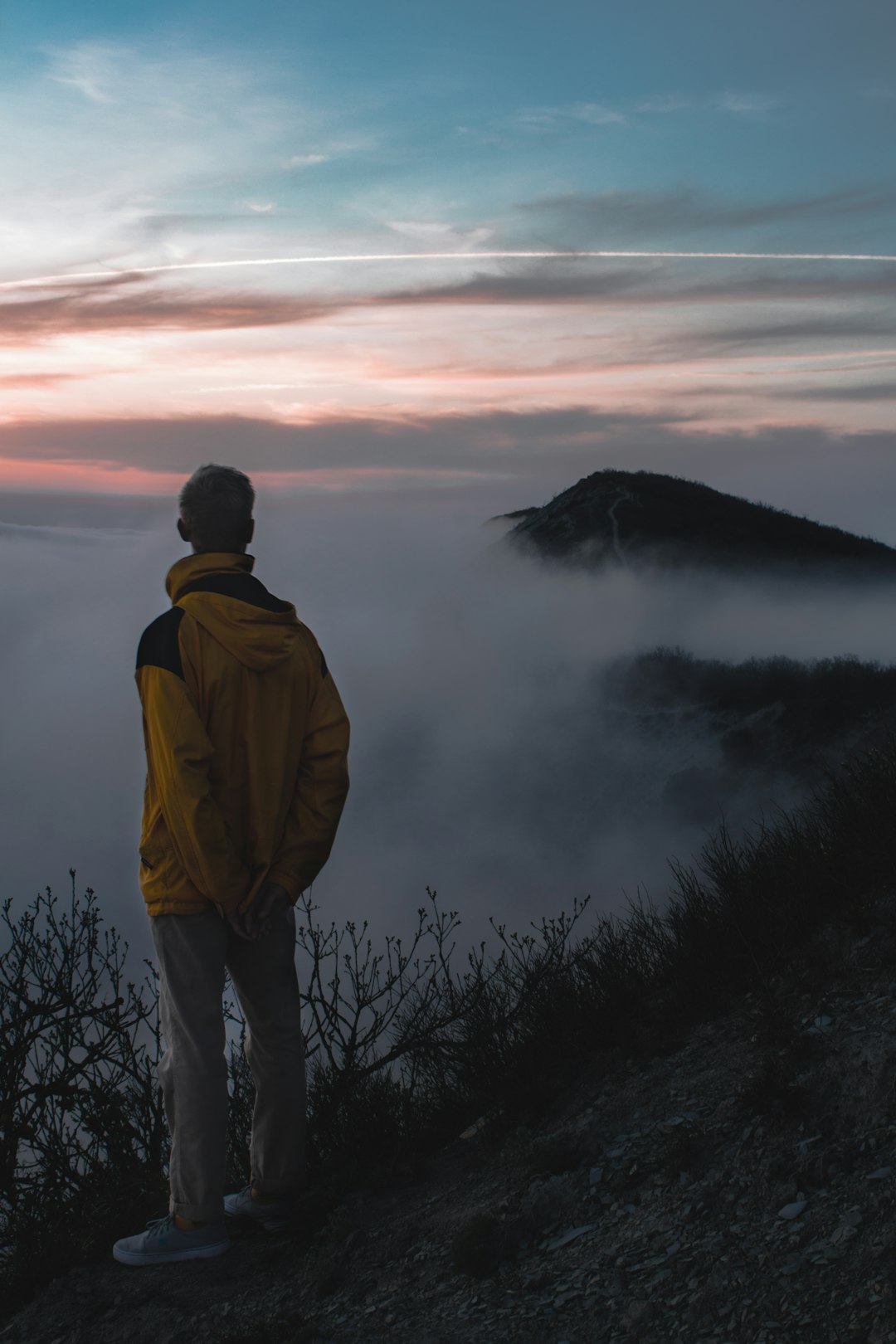 man in yellow jacket standing on top of mountain during daytime