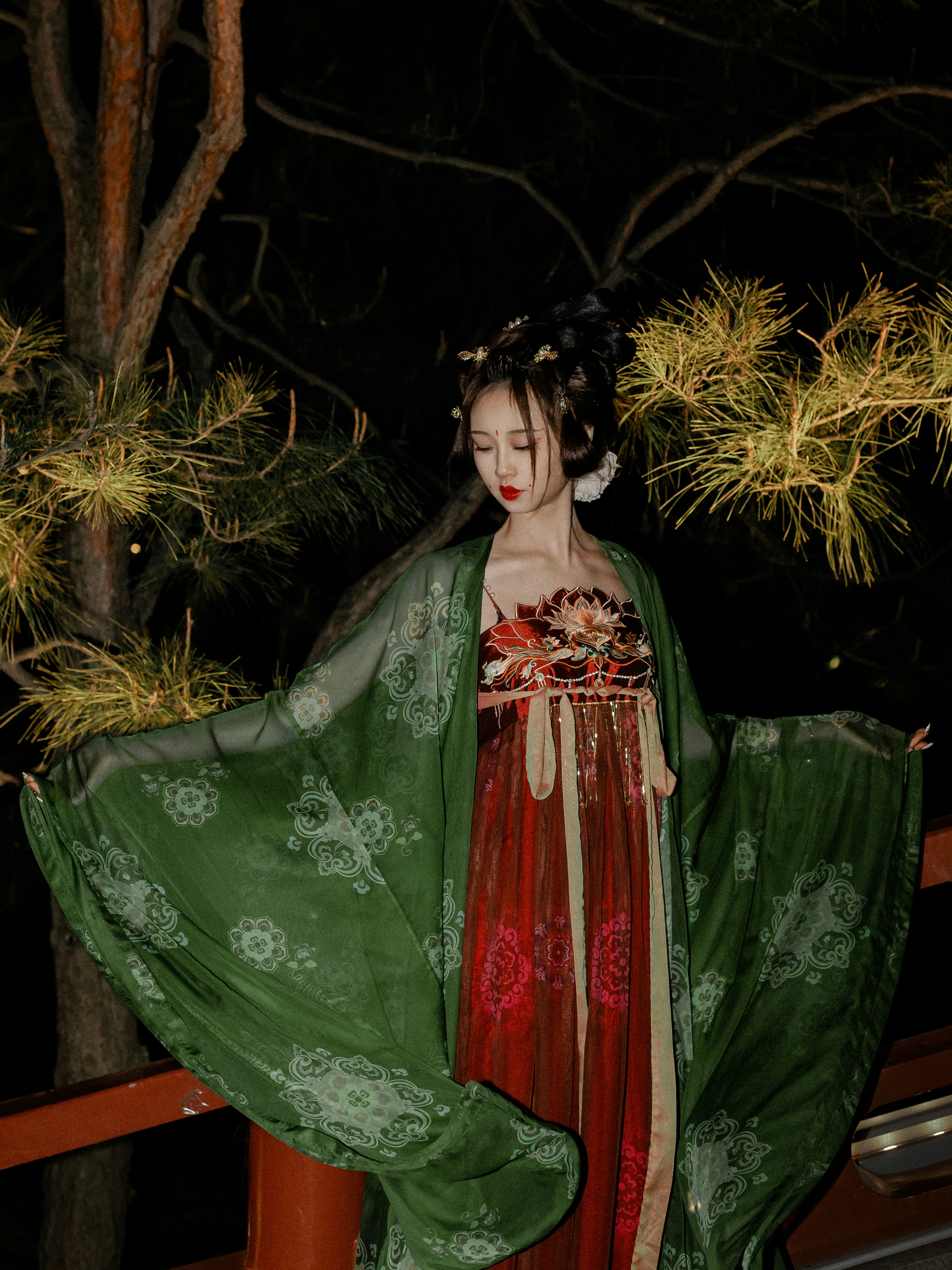 woman in green and red dress standing beside green tree