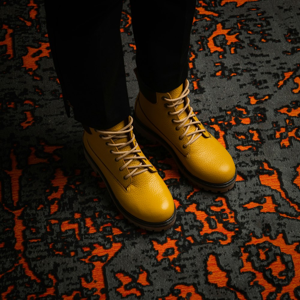 person wearing black pants and yellow and white converse all star high top sneakers