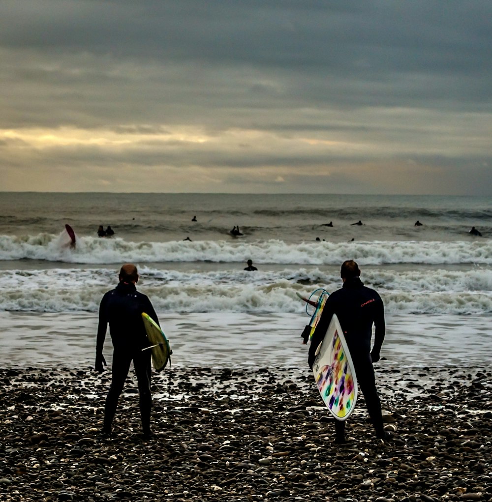 2 men walking on beach during daytime