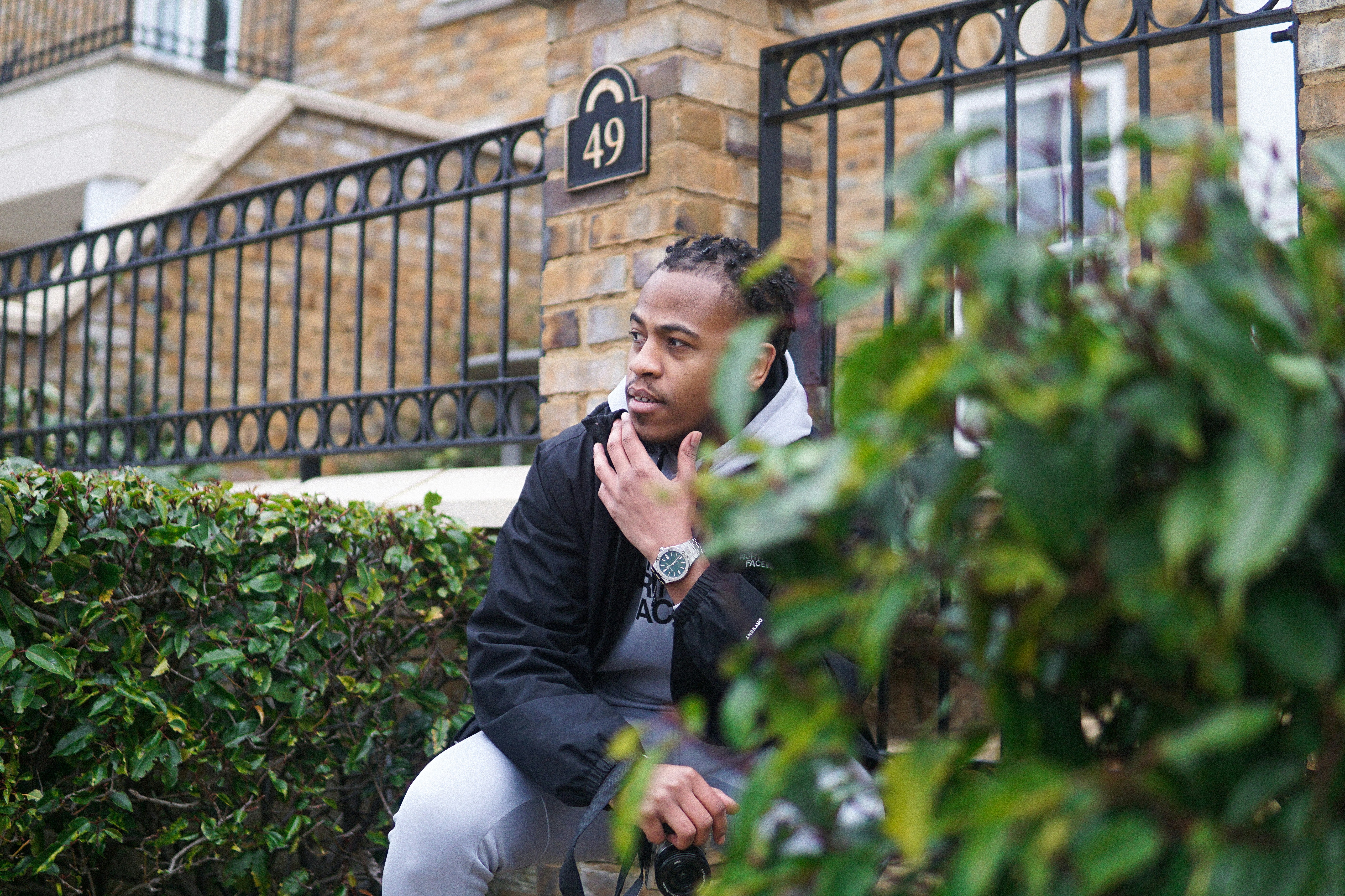 Mann in schwarzer Jacke sitzt tagsüber auf grüner Pflanze