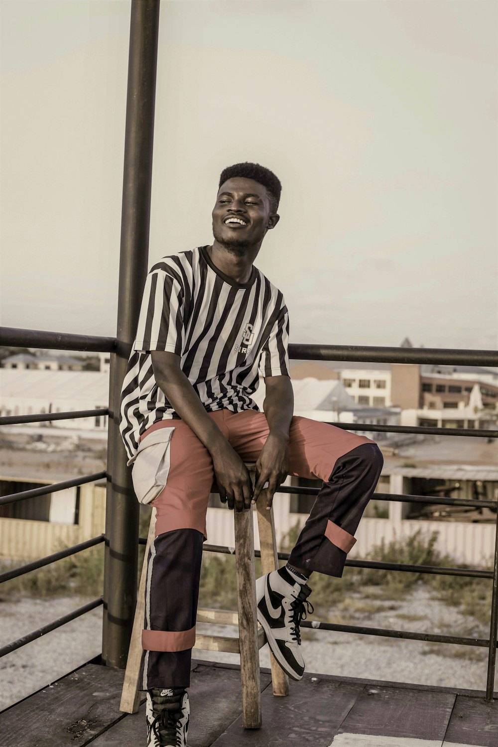 man in black and white stripe crew neck t-shirt and brown pants sitting on brown