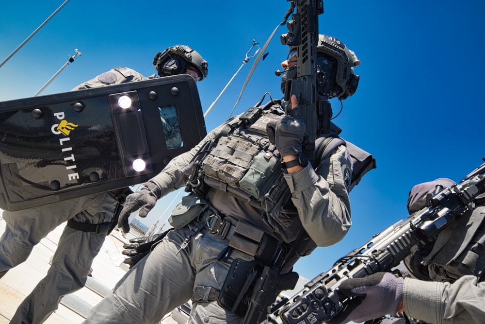 man in black and gray camouflage uniform holding rifle