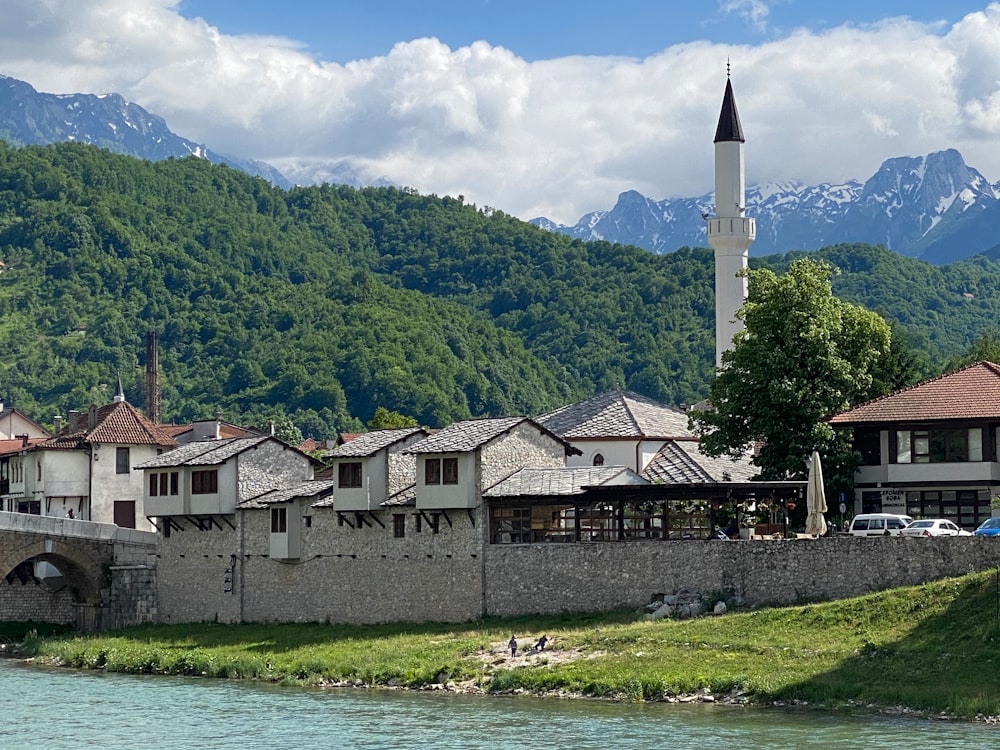 white and brown concrete building near green trees and mountain during daytime