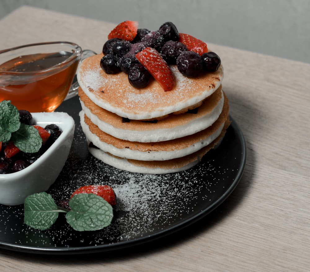 pancakes with berries and berries on black ceramic plate