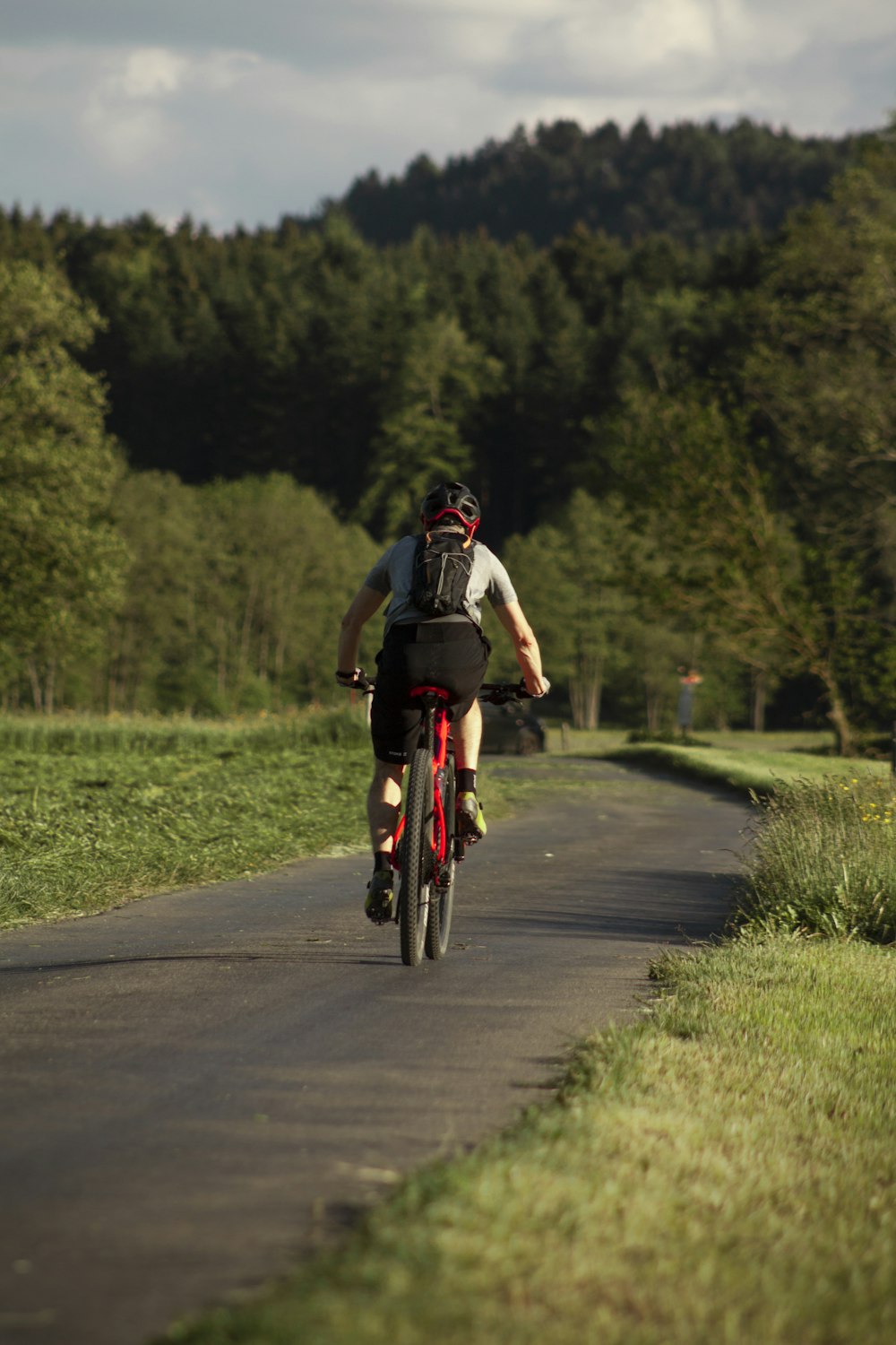 man in black and white jacket riding on red bicycle on road during daytime