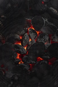 Close-up image of glowing hot charcoal briquettes in a dark setting.