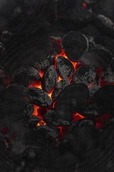 Close-up of rich black charcoal pieces glowing faintly under soft light.