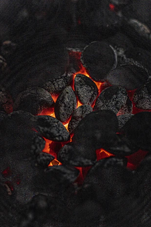 Close-up of glowing charcoal briquettes inside a classic round charcoal grill.