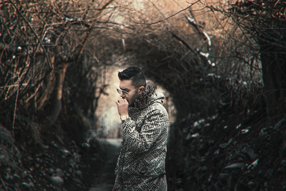 man in grey and black long sleeve shirt standing near brown bare tree during daytime