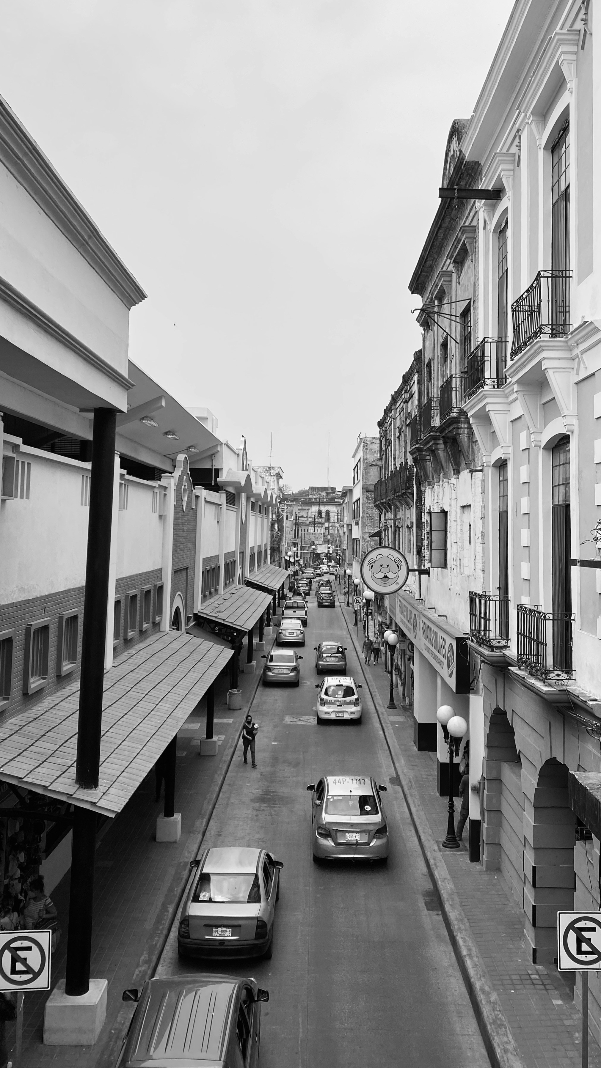grayscale photo of cars parked on sidewalk near buildings