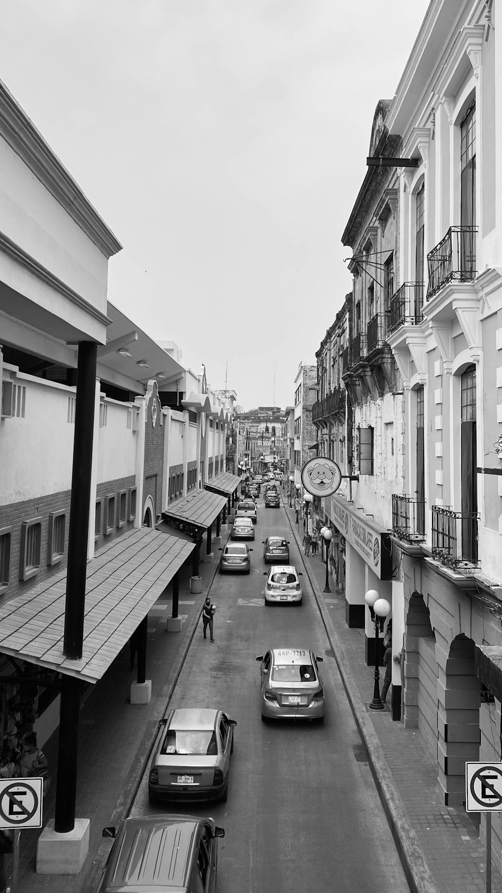 grayscale photo of cars parked on sidewalk near buildings