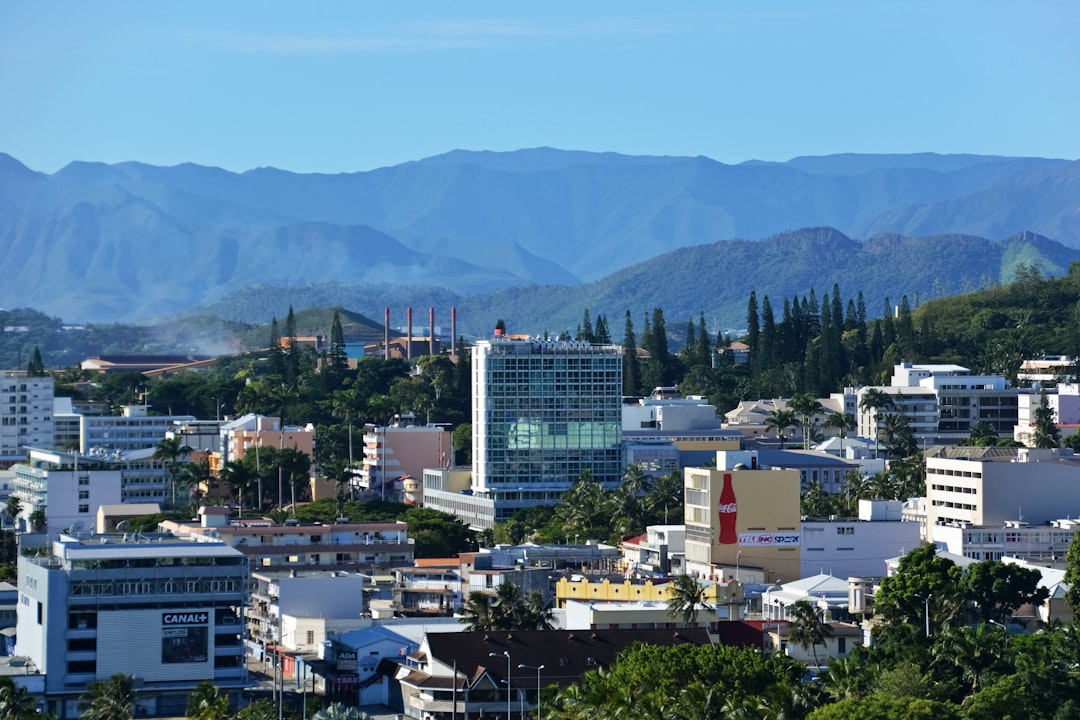 white and black concrete buildings near green mountain under blue sky during daytime