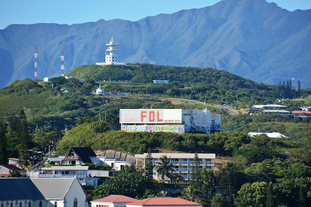 white and black concrete building near green trees and mountain during daytime