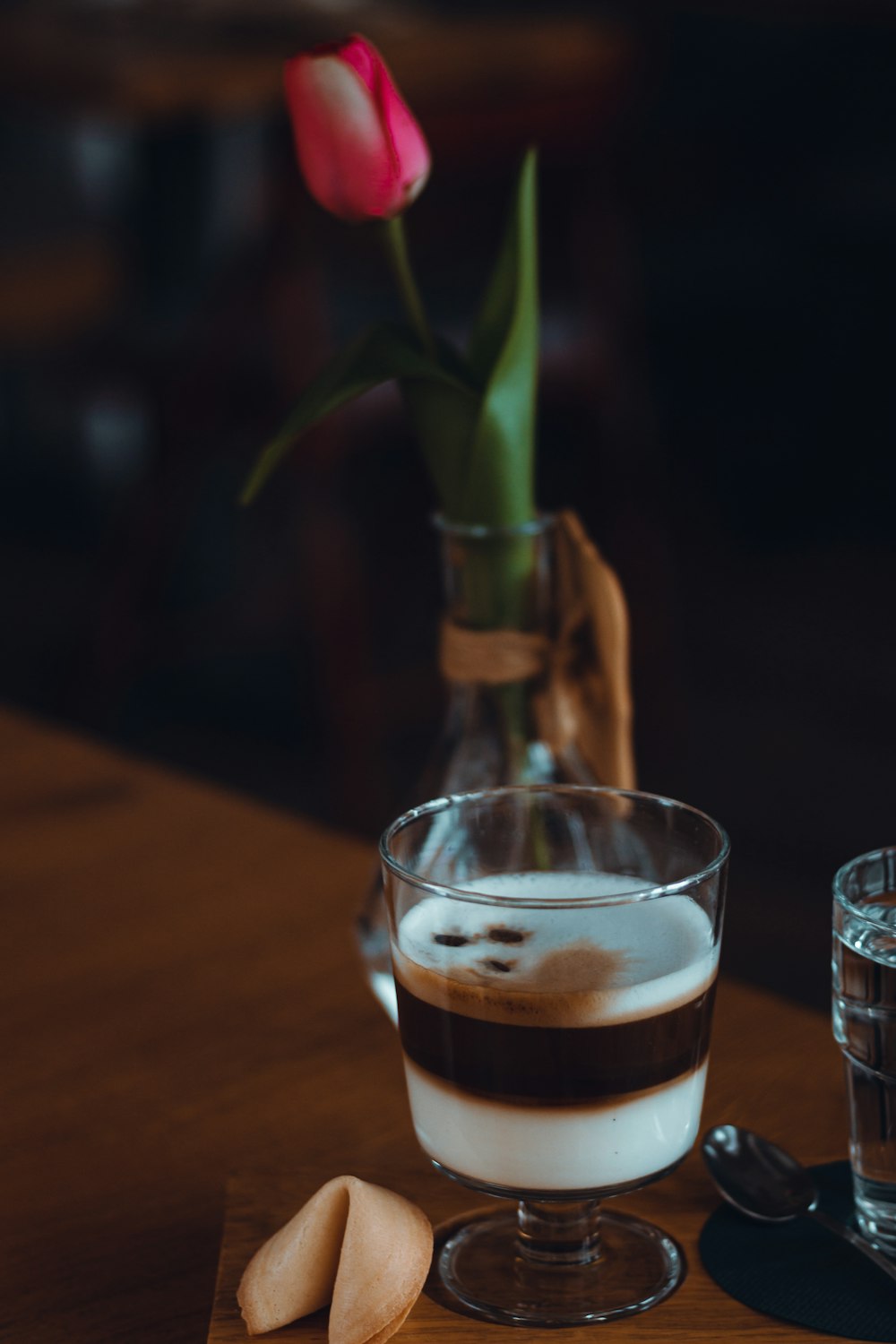 clear drinking glass with brown liquid on brown wooden table