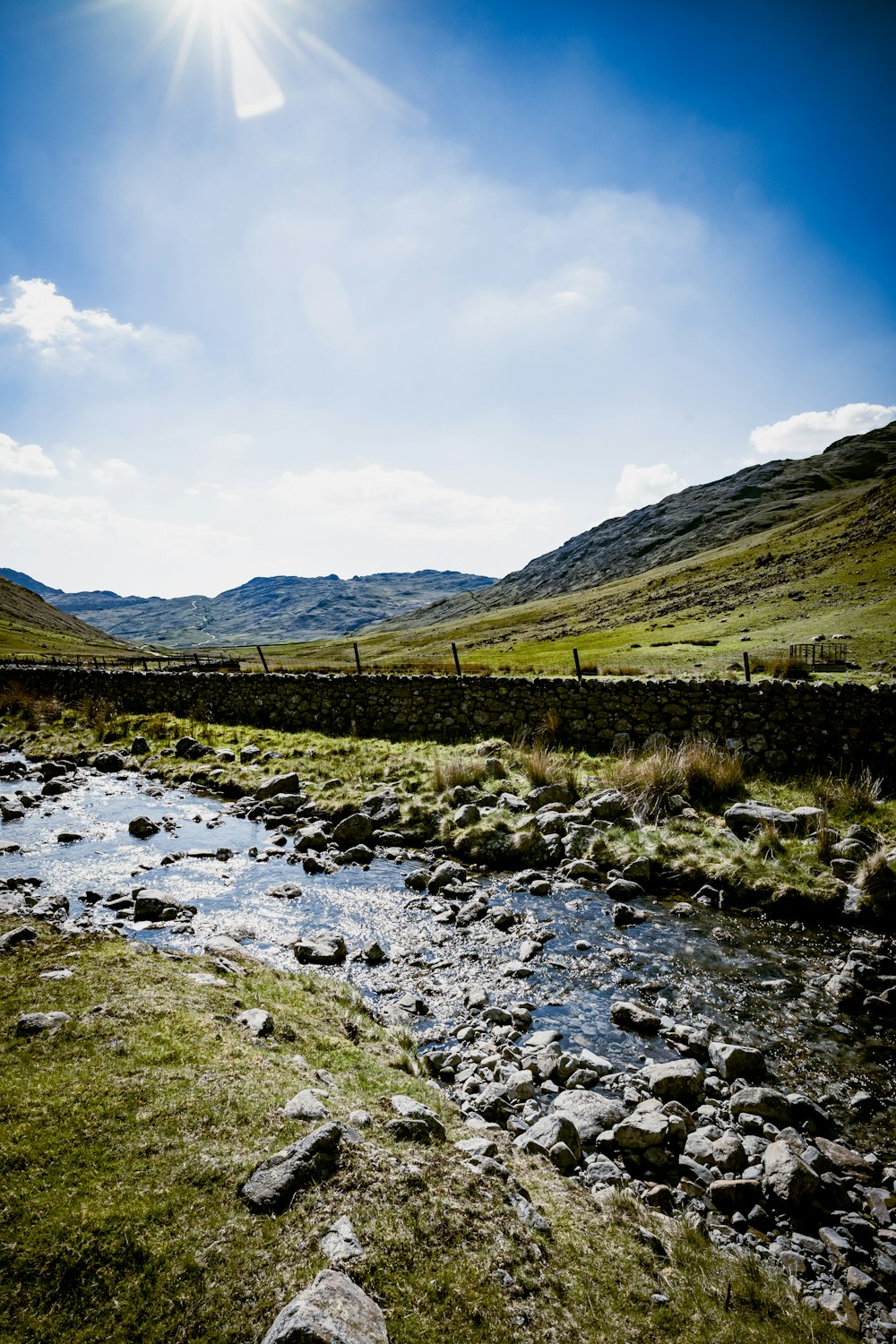 green grass field and mountain under blue sky during daytime