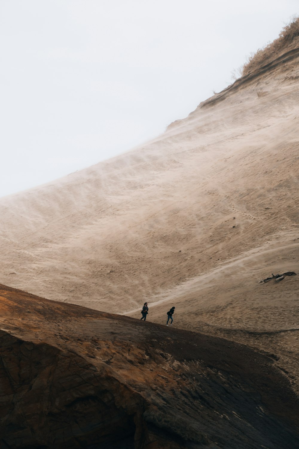 2 persone che camminano sulla montagna rocciosa marrone durante il giorno