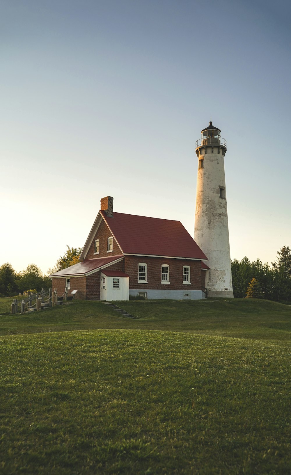 white and brown concrete lighthouse on green grass field under white clouds during daytime