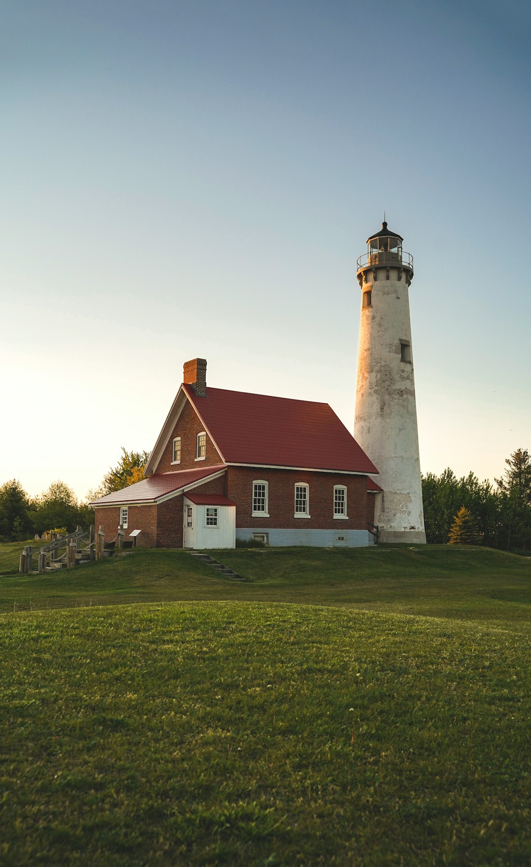 white and brown concrete lighthouse on green grass field under white clouds during daytime