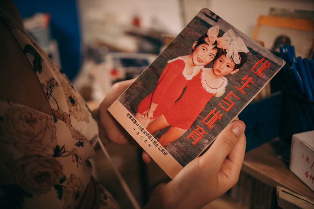 person holding a book with a girl in red dress