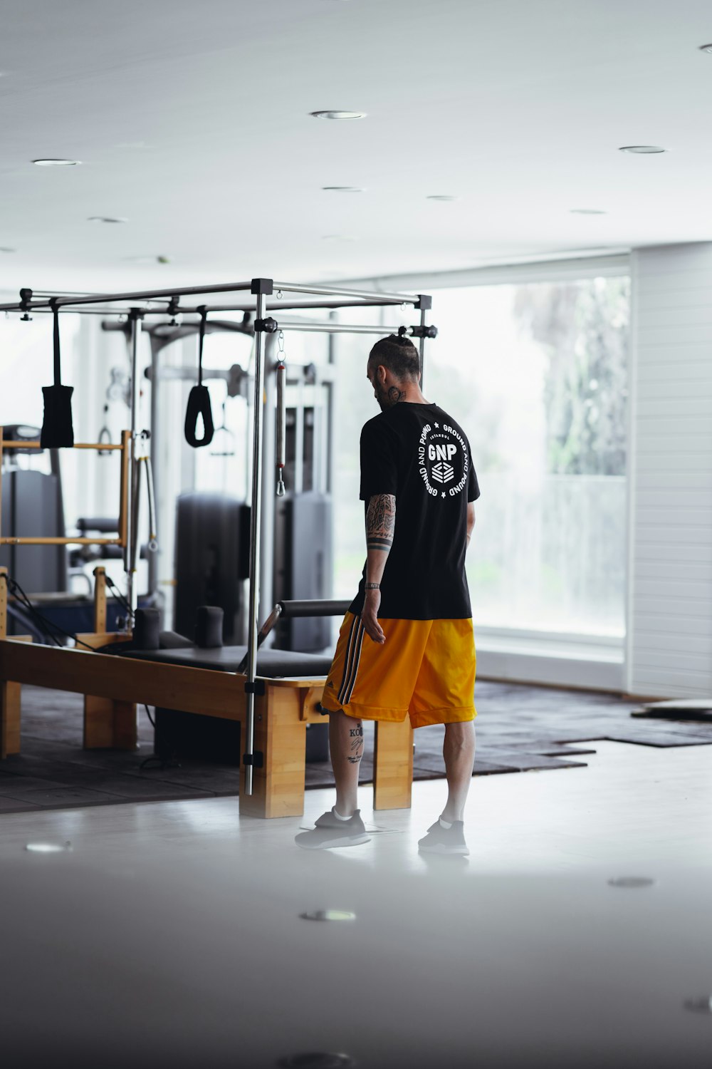 man in black t-shirt and yellow shorts standing near exercise equipment