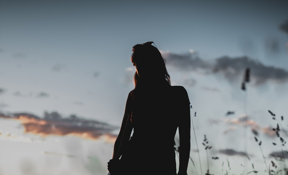 Femme en chemise à manches longues noire debout sur le terrain pendant la journée