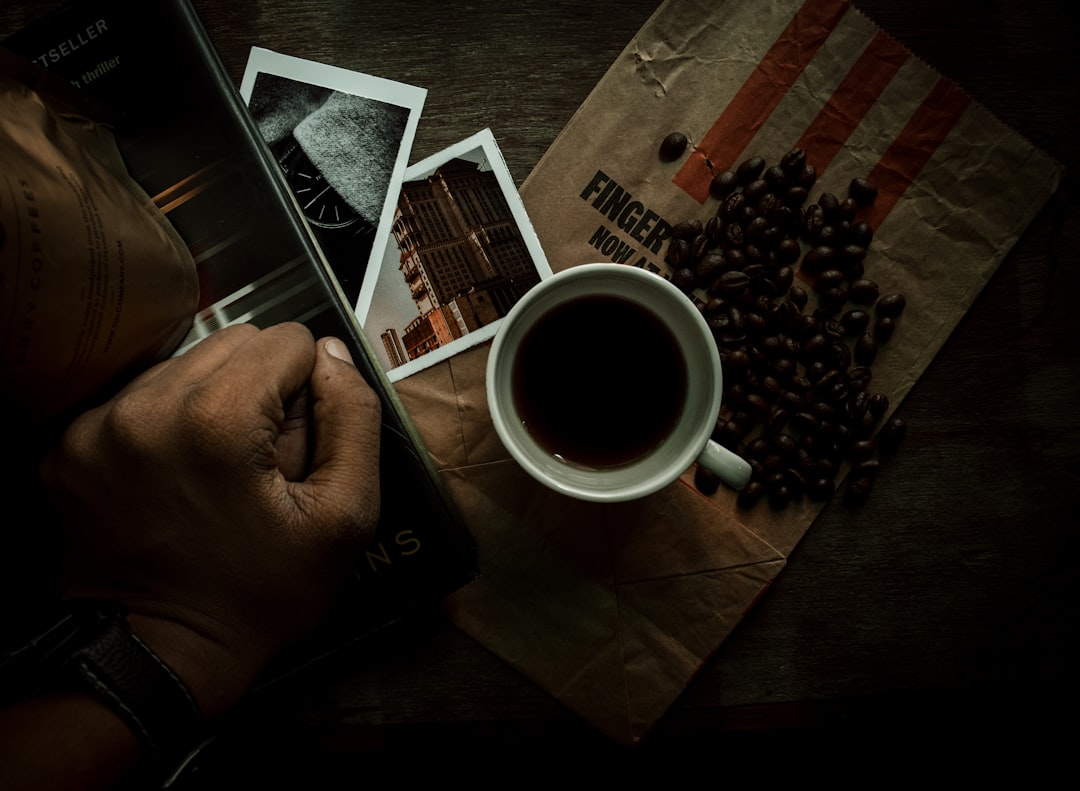 person holding white ceramic mug with black liquid