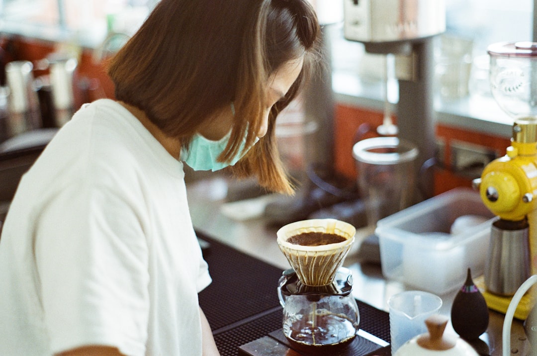 woman in white shirt holding clear glass mug