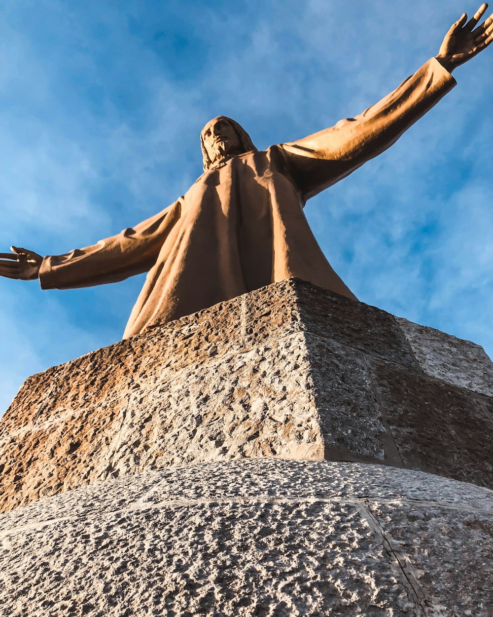 Photographie en contre-plongée d’une statue d’homme sous le ciel bleu pendant la journée