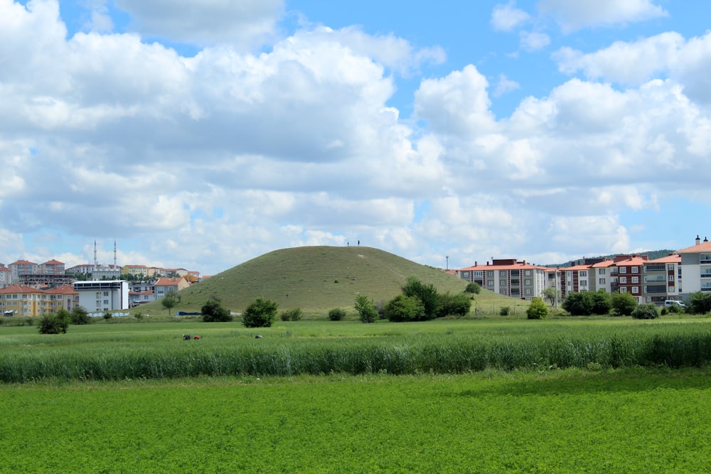 green grass field near white building under white clouds during daytime