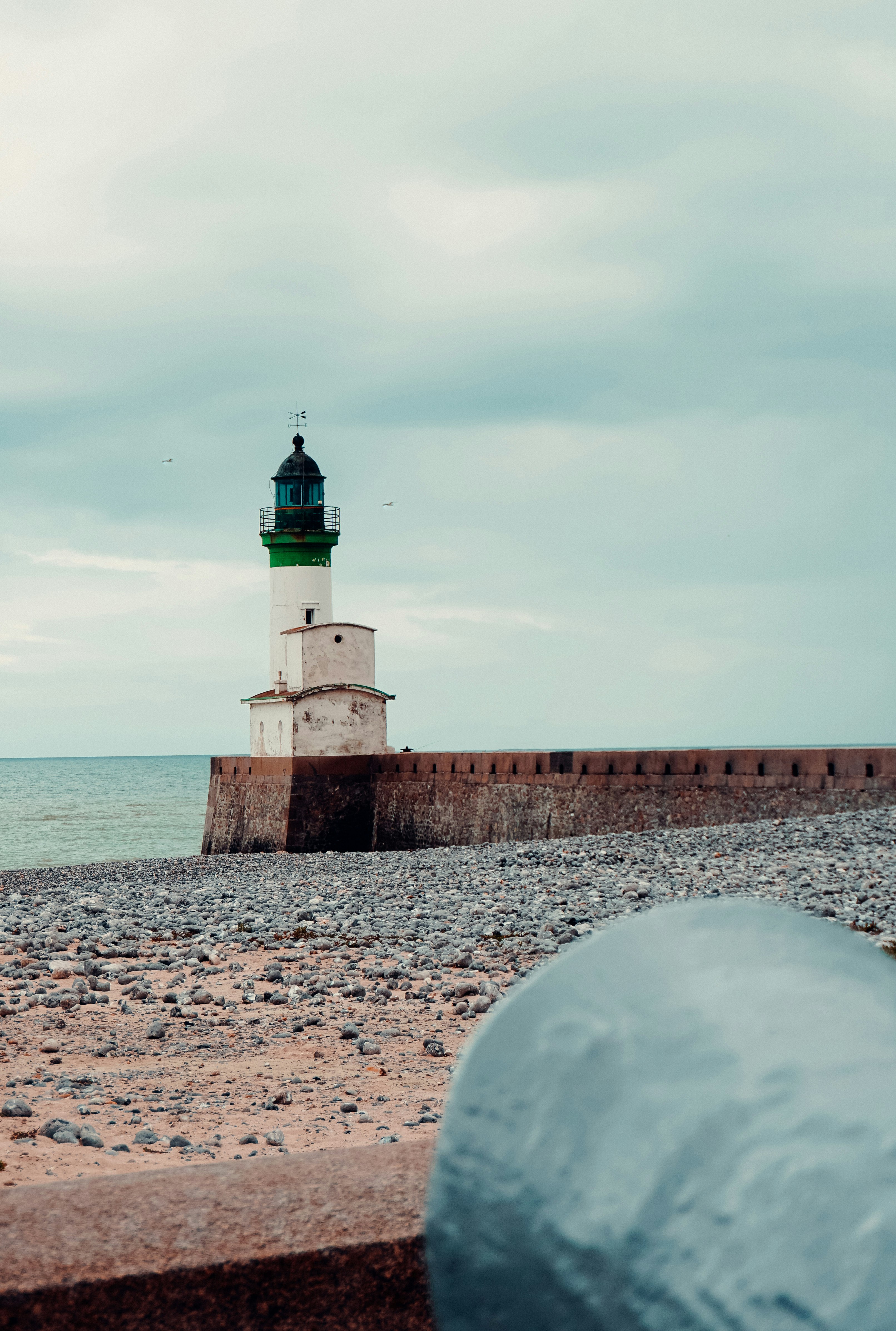 white and black lighthouse near body of water during daytime