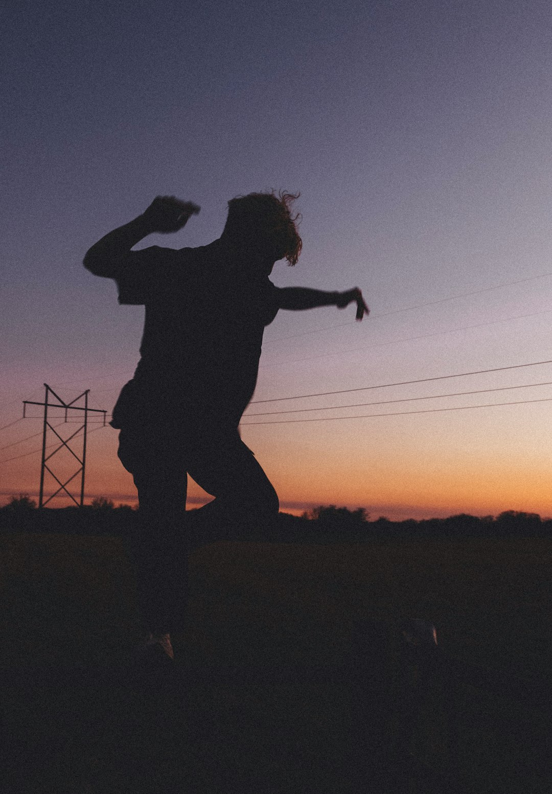 silhouette of man standing on grass field during sunset