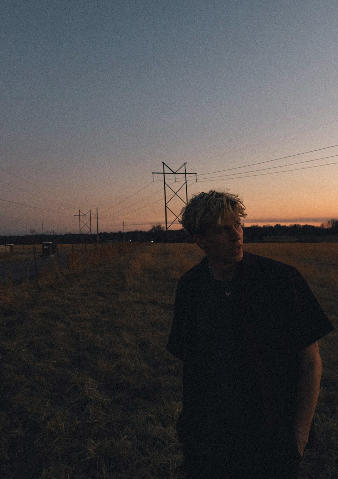 man in black crew neck t-shirt standing on green grass field during sunset