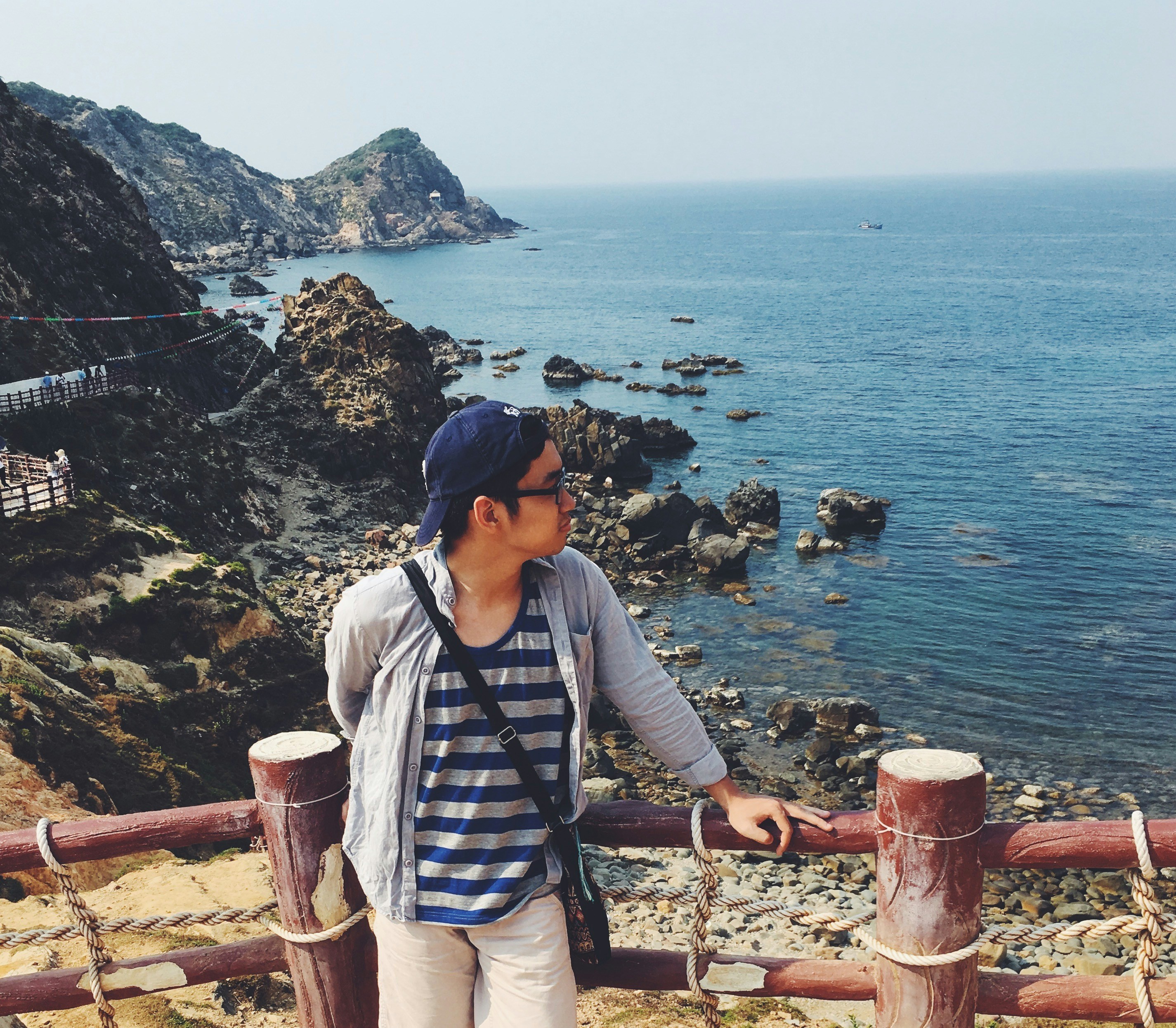 homme en chemise à manches longues rayée blanche et noire debout sur une clôture en béton brun près du corps