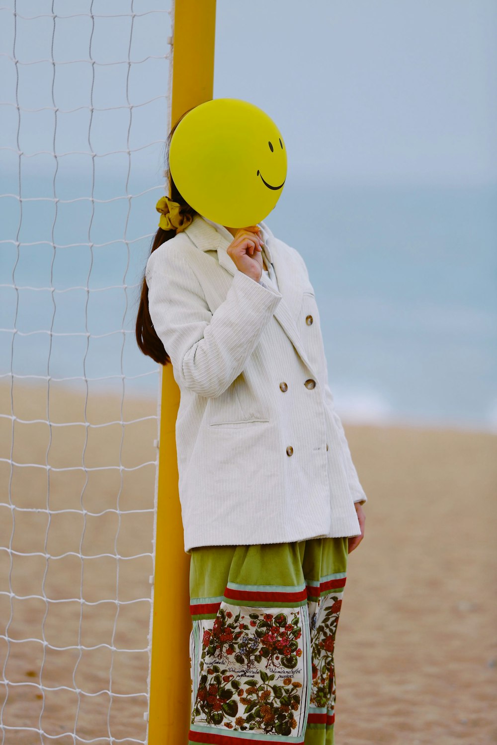 woman in white coat and green skirt standing beside yellow volleyball net during daytime