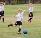 4 women playing soccer on green grass field during daytime