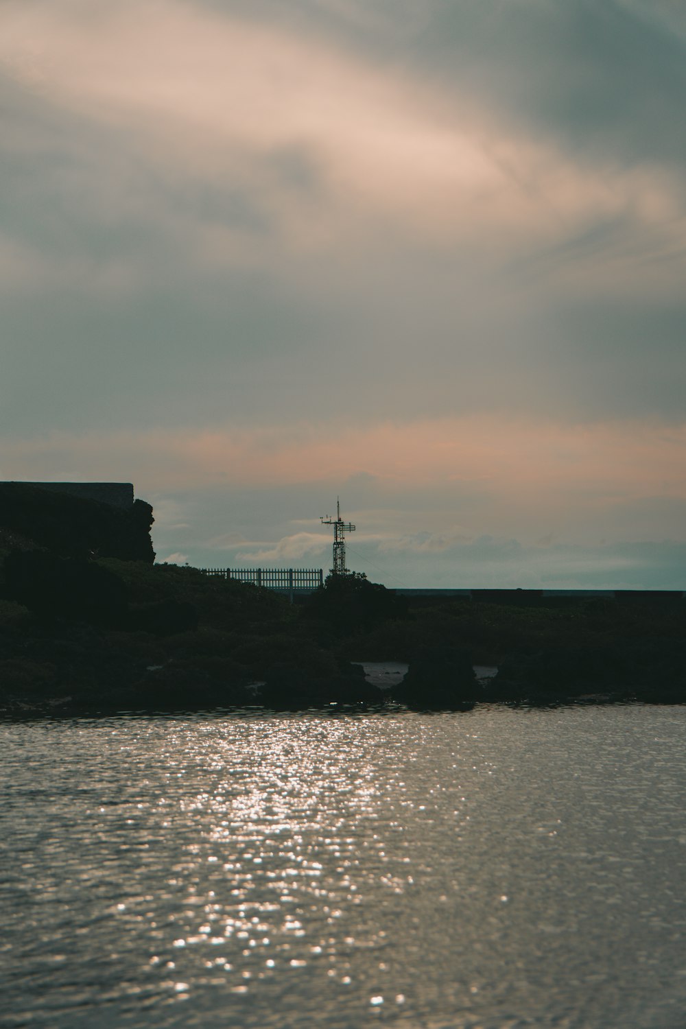 silhouette of building near body of water during sunset