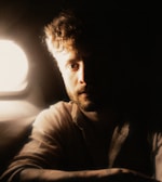 Close-up of a hand gently touching a dark, textured beard under warm amber light.