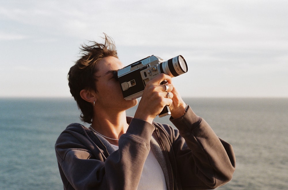 uomo in giacca grigia che tiene la macchina fotografica in bianco e nero